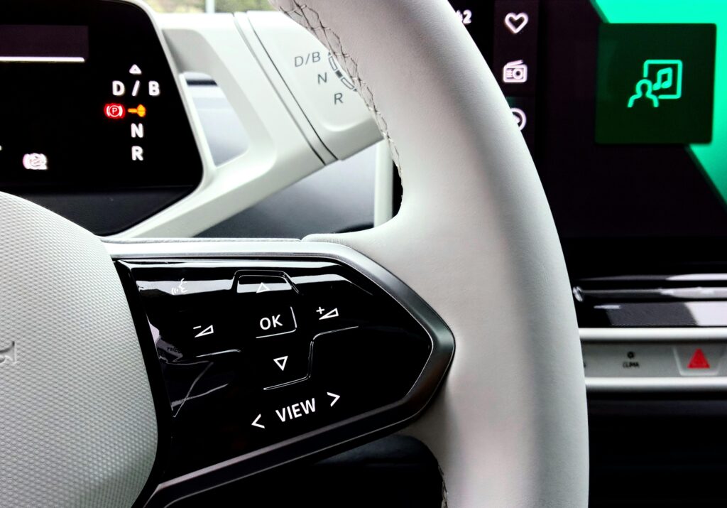 Detailed view of a car's steering wheel and control buttons, showcasing modern design and technology.